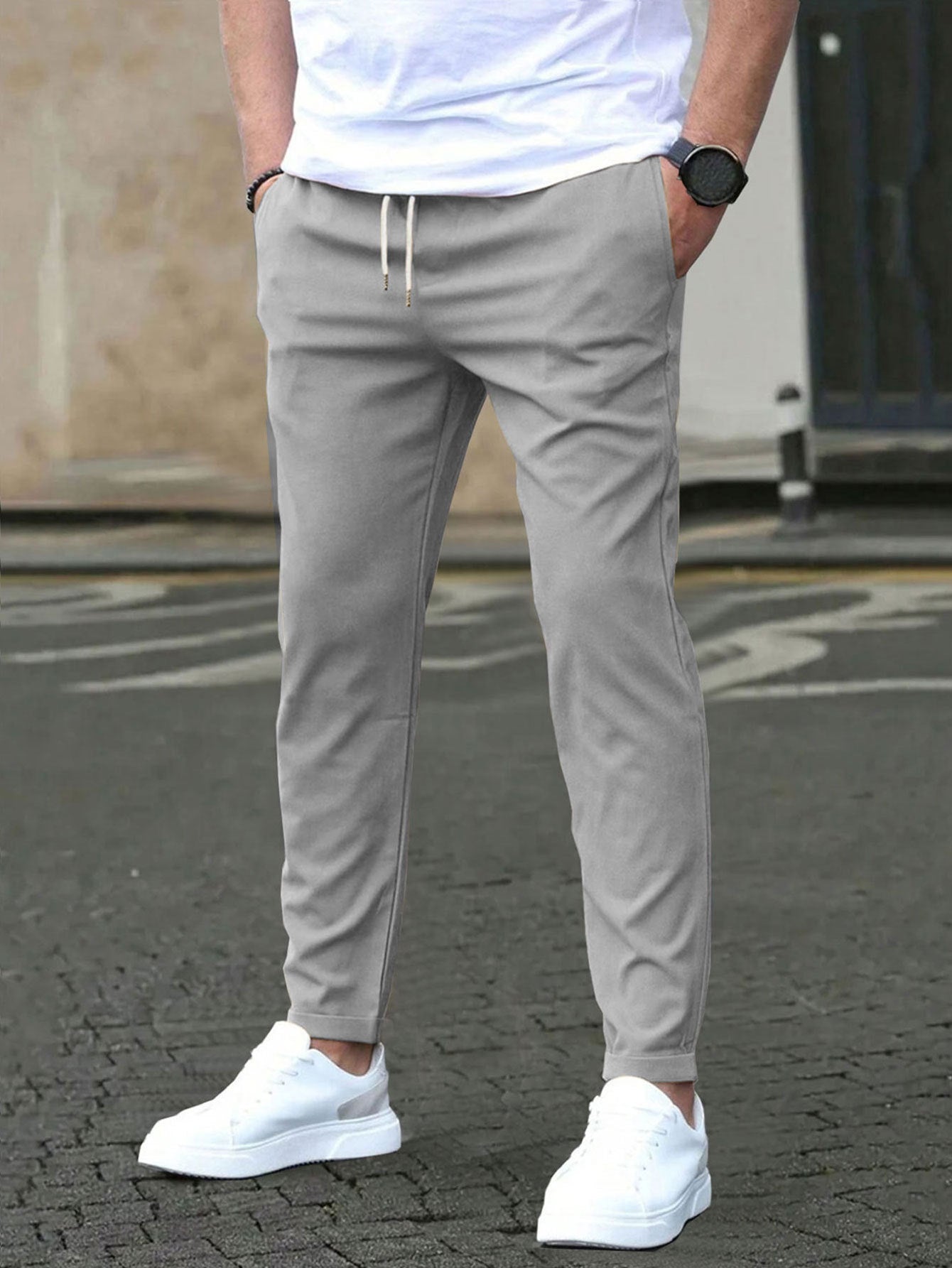 Person wearing light green jogger pants with a white shirt and white sneakers on a street.
