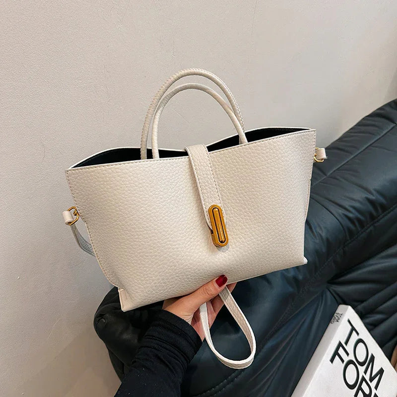 White handbag held by a person with a neutral background