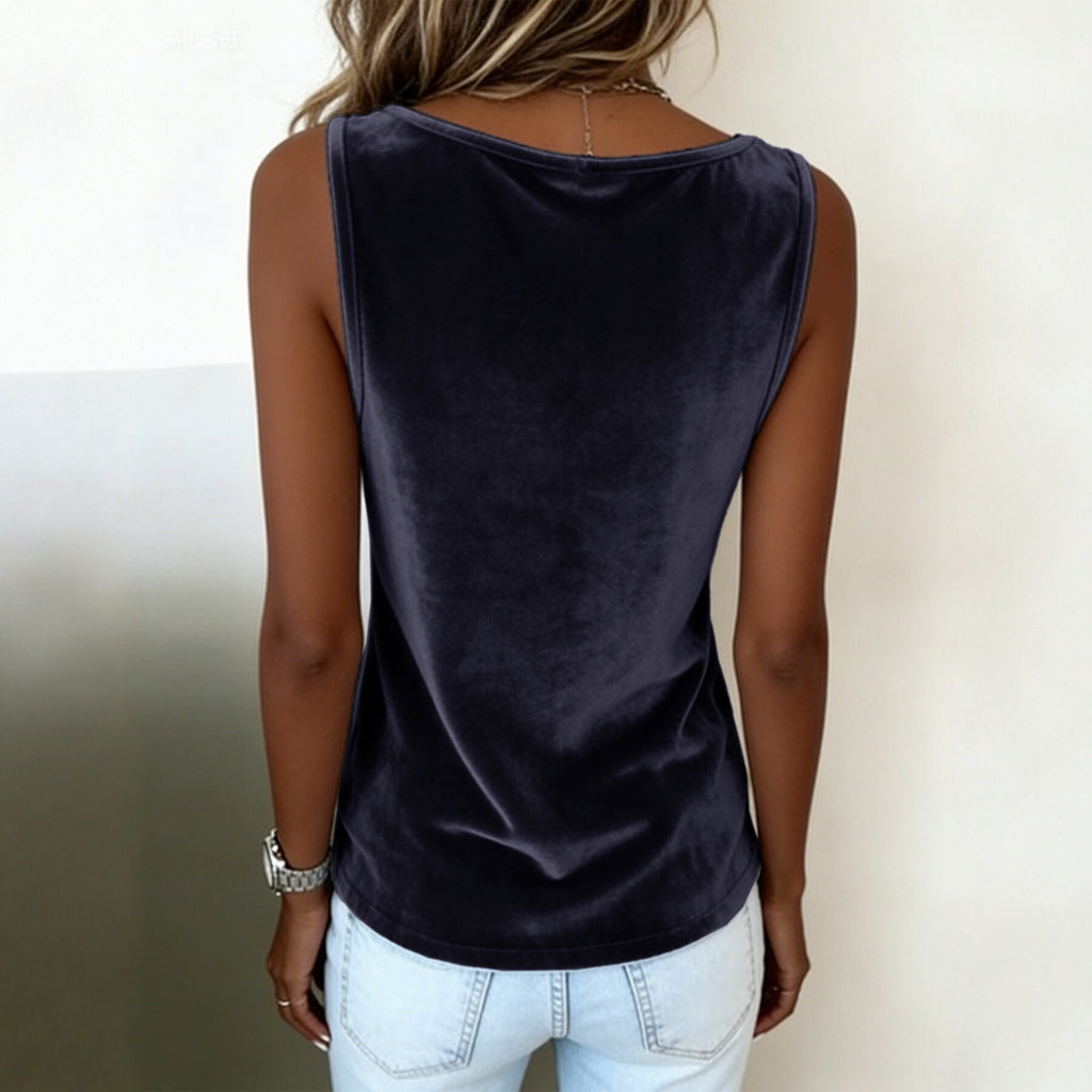 Person wearing a dark purple sleeveless top and light blue jeans against a neutral background