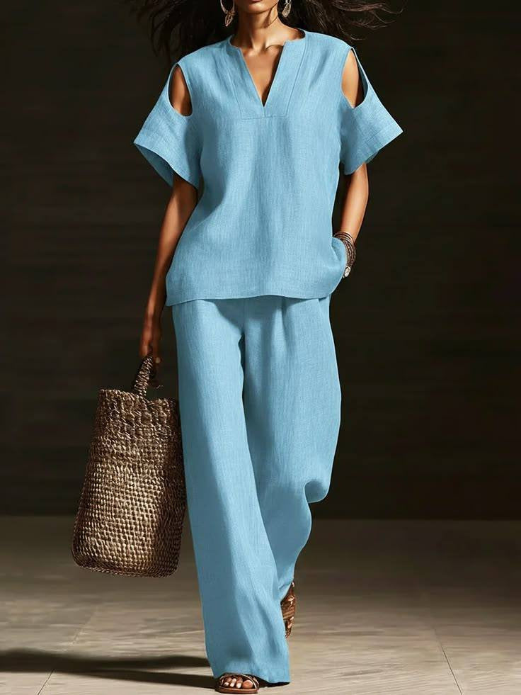 Woman in a blue outfit holding a woven bag against a dark background