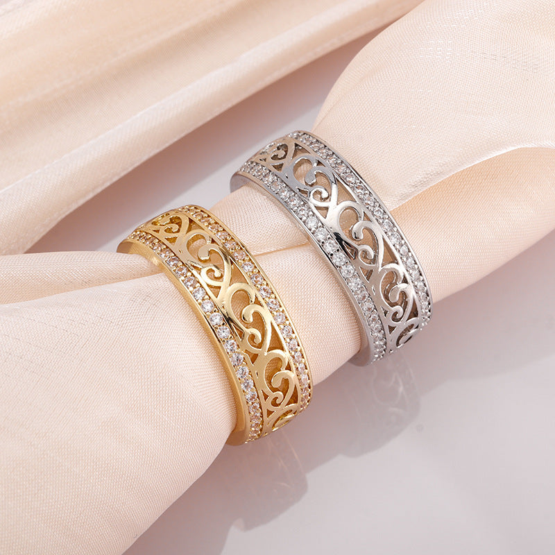 Two gold and silver rings with intricate designs on a beige fabric background