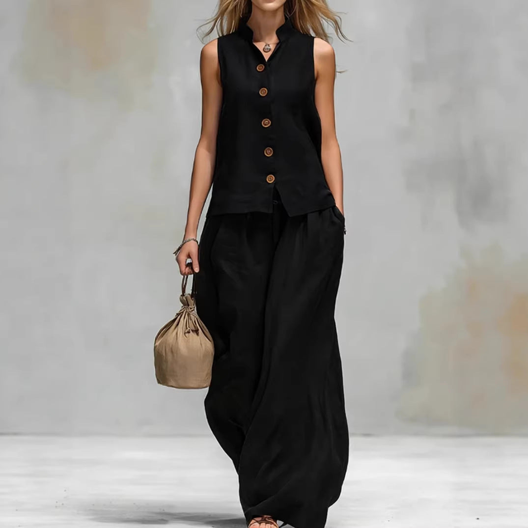 Person wearing a black sleeveless top and wide-leg pants holding a beige handbag against a neutral background
