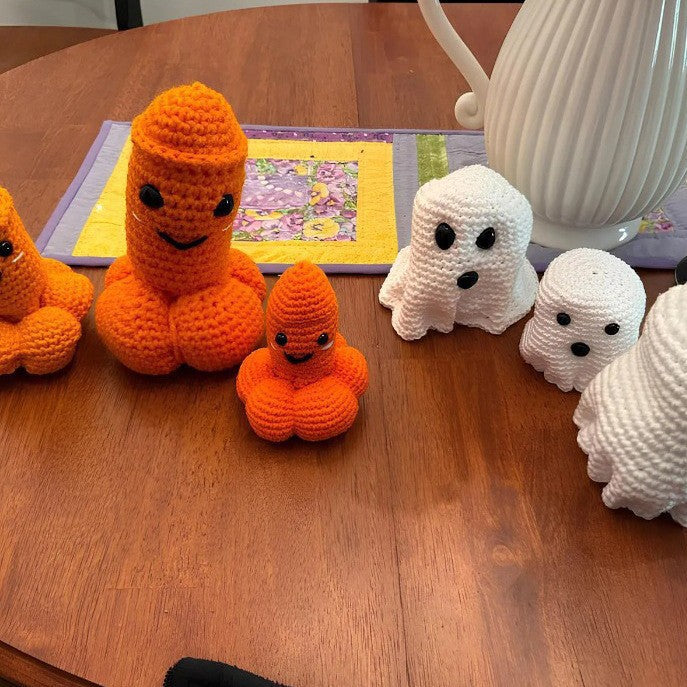 Knitted orange and white ghost toys on a wooden table