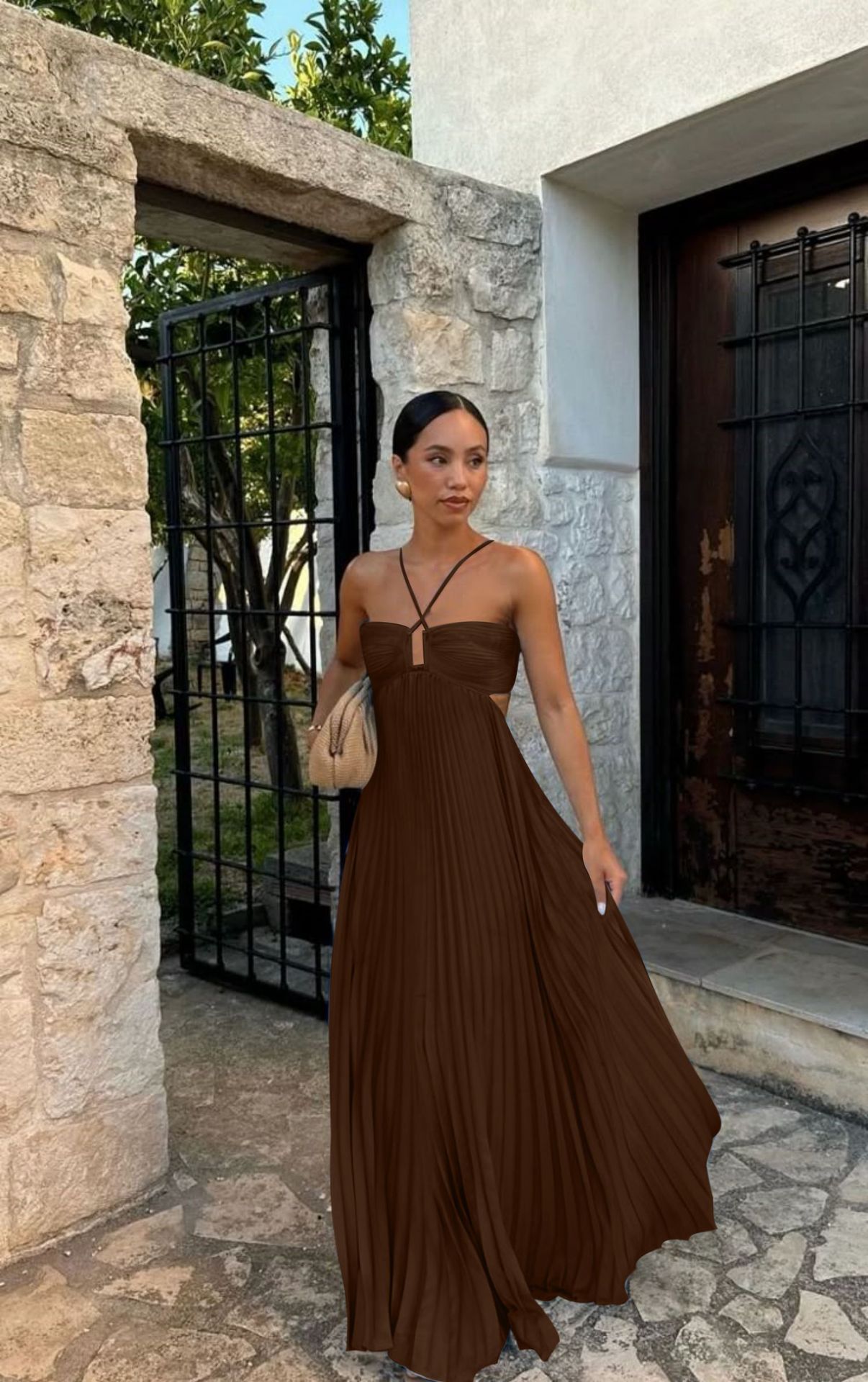 Woman in a brown dress standing in front of a stone building.