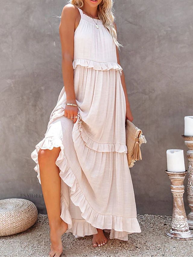 Woman wearing a white and beige layered dress against a gray wall.