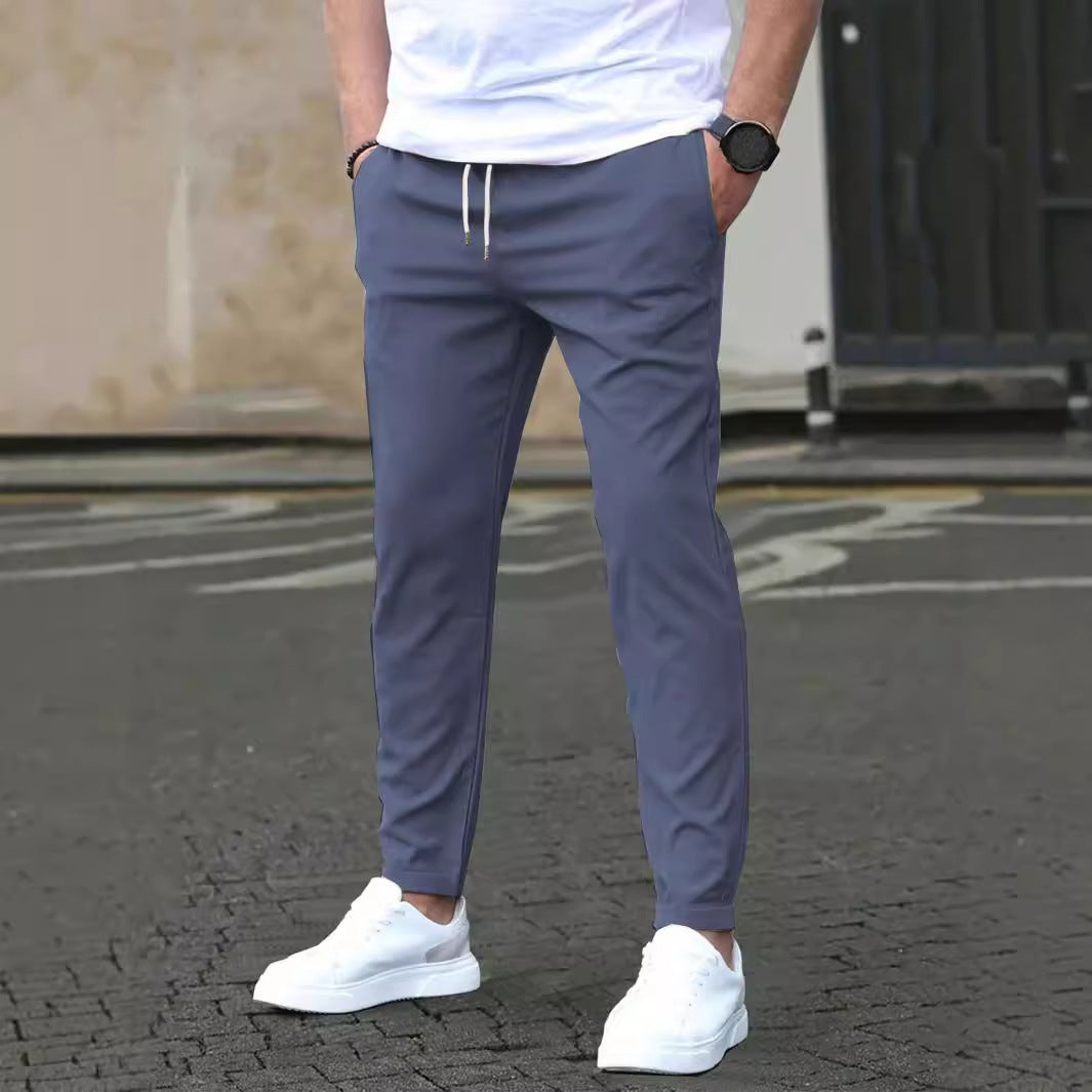Person wearing gray pants and white sneakers on a street.