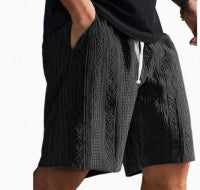 Person wearing black knit shorts with a white background