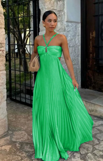 Woman in a green dress standing outdoors near a stone wall.