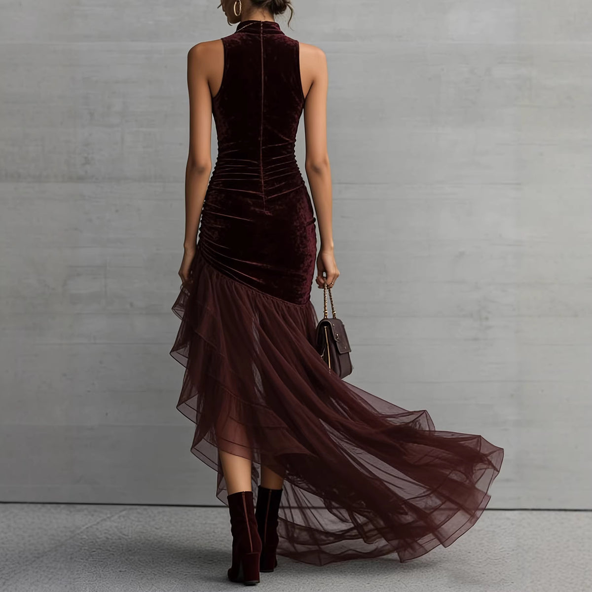 Woman wearing a burgundy velvet dress with sheer overlay against a gray concrete wall.