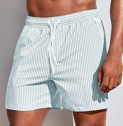 White and blue striped swim shorts worn by a person on a neutral background
