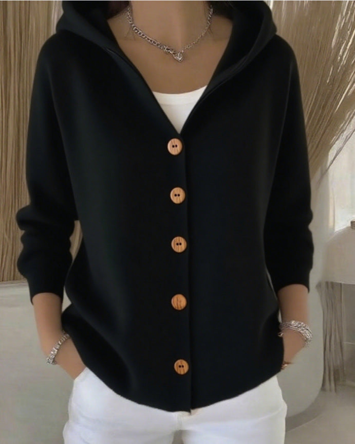 Person wearing a black cardigan with wooden buttons indoors