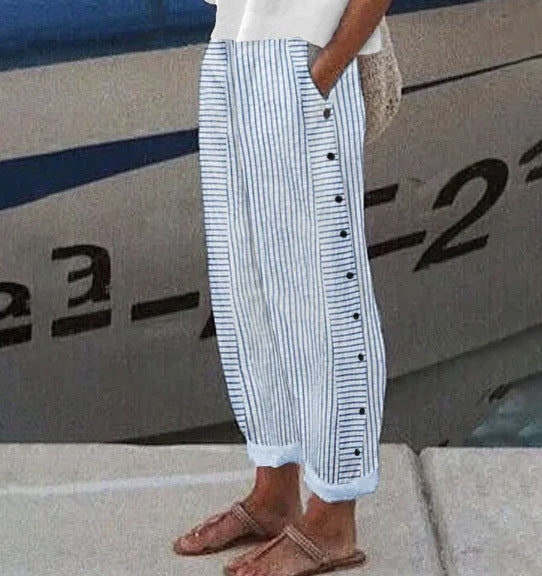 Person wearing blue and white striped pants with buttons, standing in front of a boat.