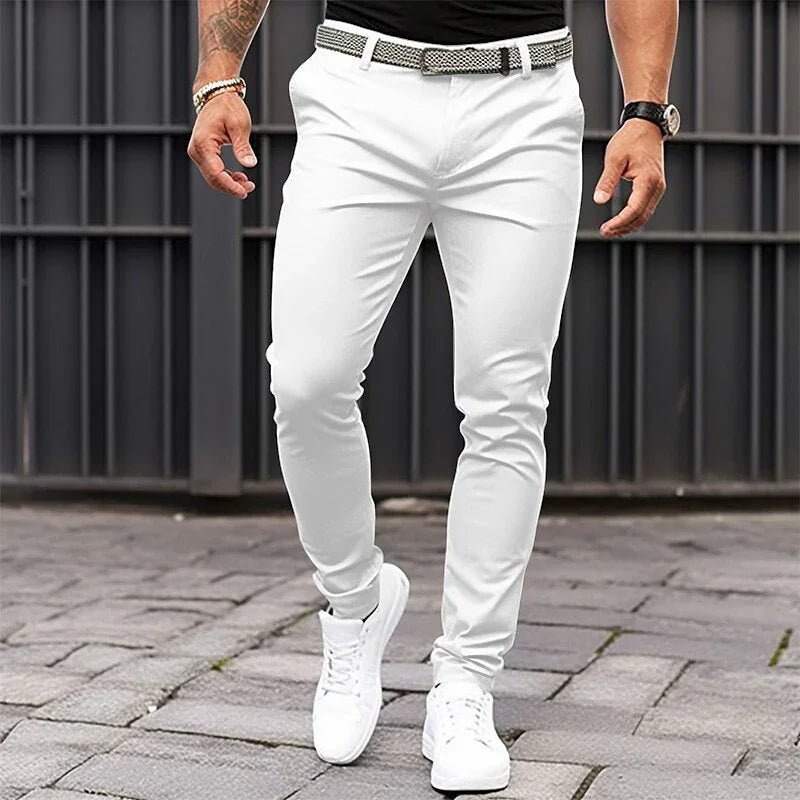 Person wearing white pants and white sneakers on a paved surface with a metal railing in the background.