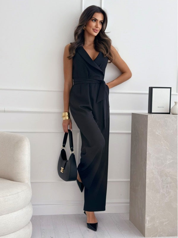 Woman in a black jumpsuit holding a handbag in an indoor setting