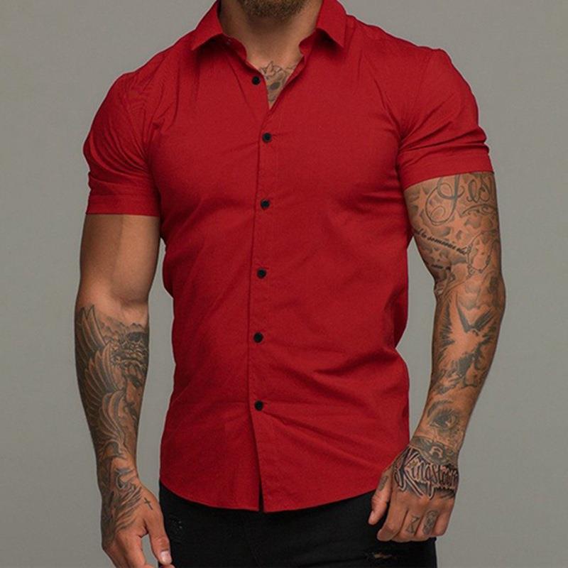 Man wearing a red button-up shirt with tattoos on arms against a gray background