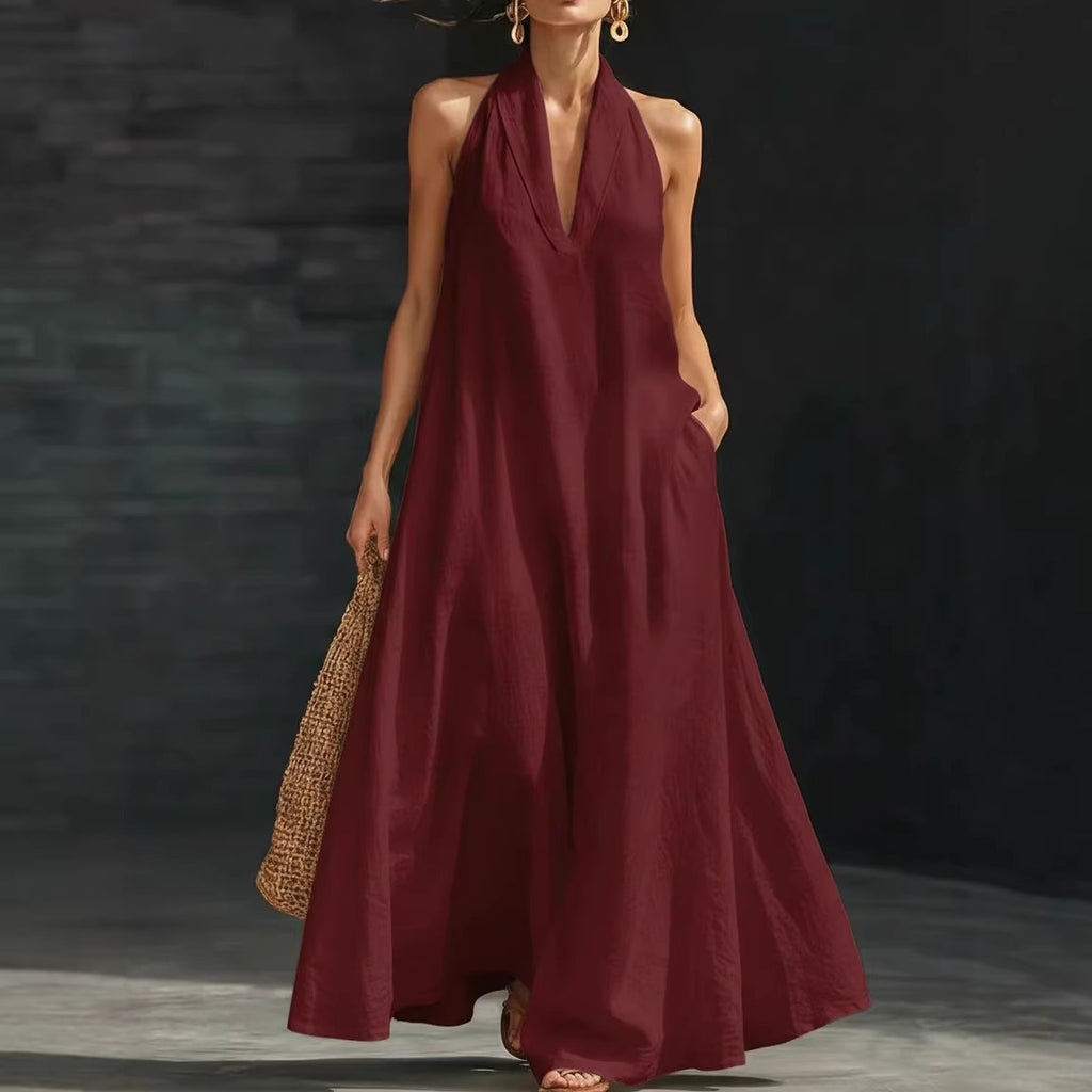 Woman wearing a burgundy halter neck dress against a dark background