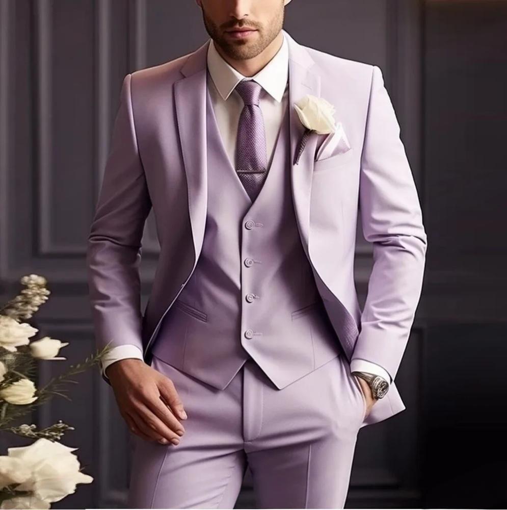 Man wearing a light purple suit with a white flower in his pocket, standing against a dark background.