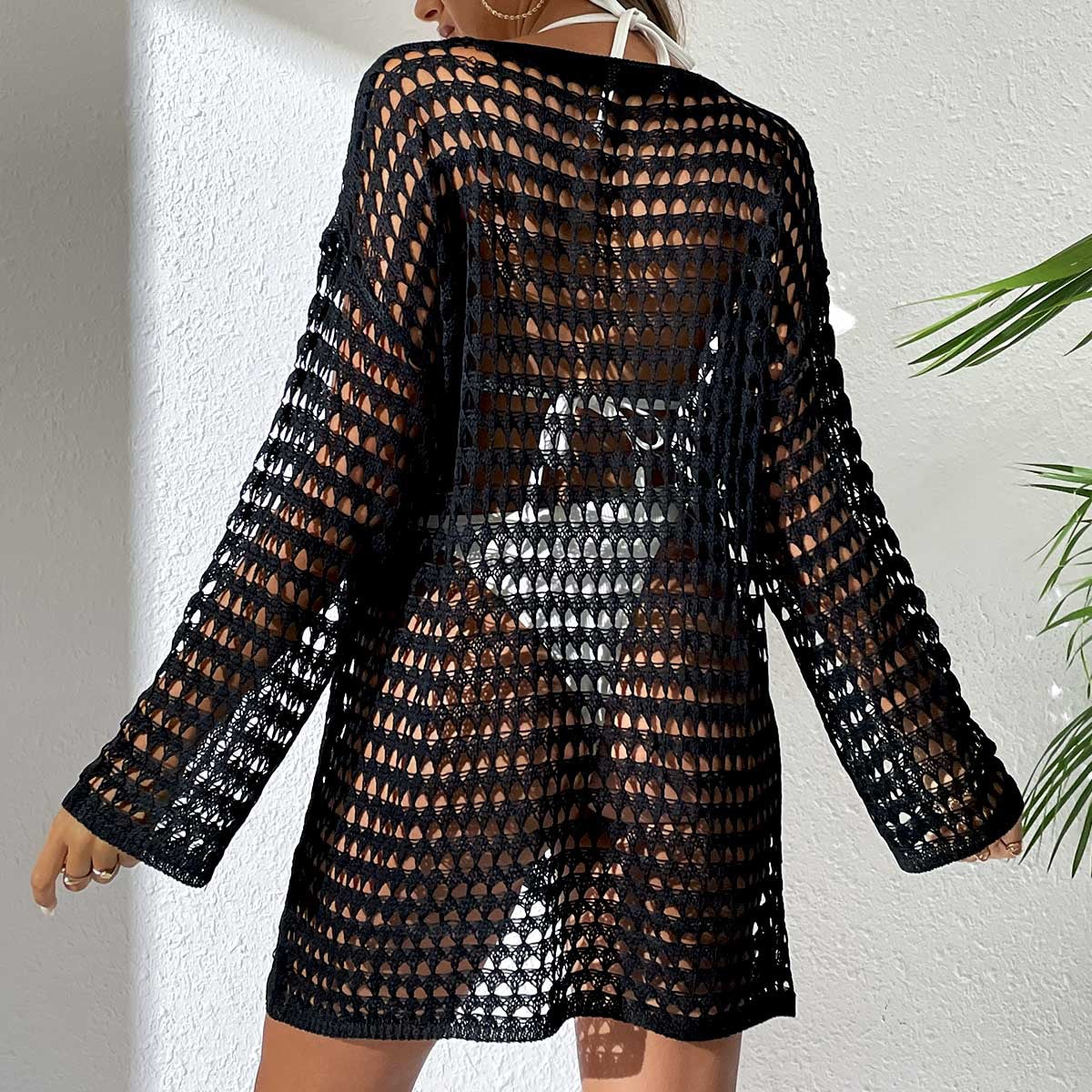 Black crochet dress worn by a person against a white wall.