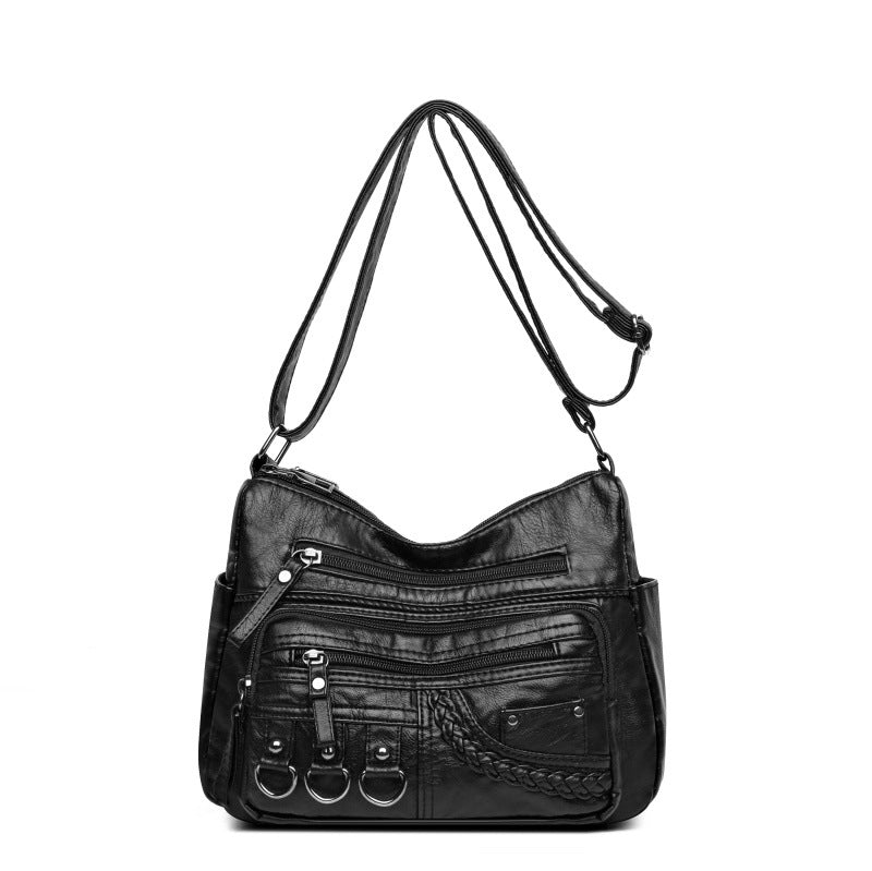 Black handbag with multiple pockets and zippers on a white background