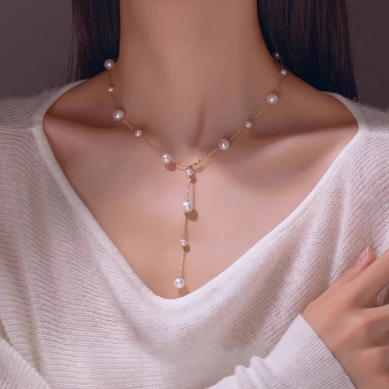 Pearl necklace worn by a person in a white sweater