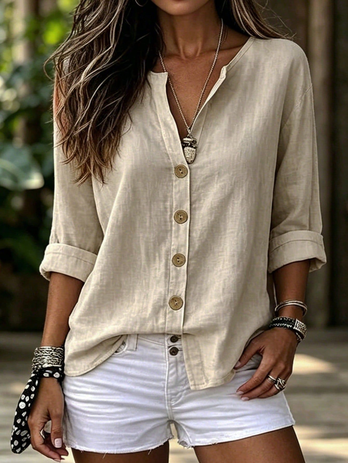 Woman wearing a beige button-up shirt and white shorts with a blurred natural background