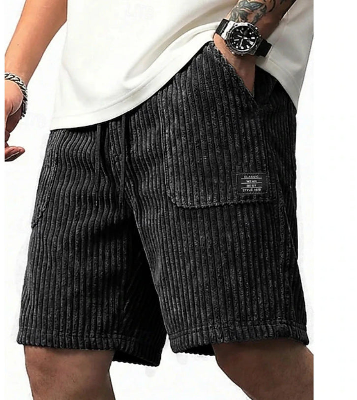 Person wearing dark gray corduroy shorts with a white background