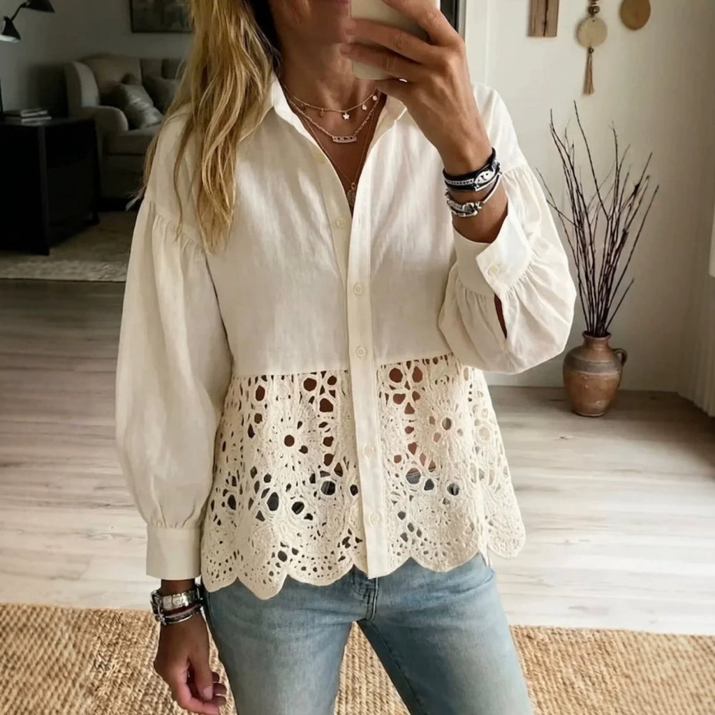 A woman takes a mirror selfie wearing a cream-colored blouse with long puff sleeves and a sheer eyelet lace peplum hem, paired with light blue jeans.