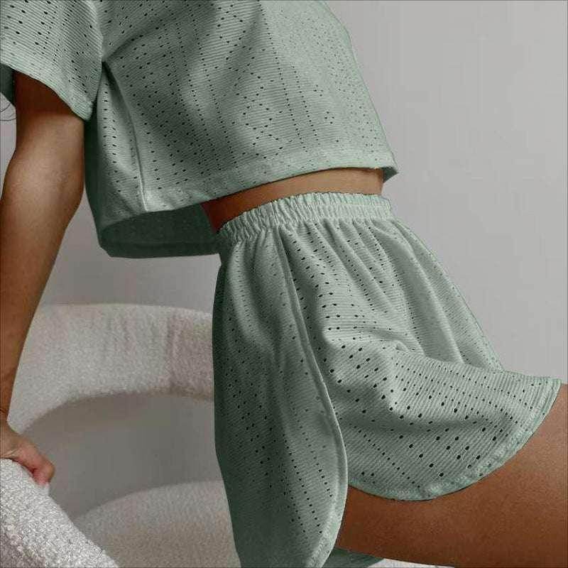 Woman wearing sage green eyelet lounge set from ZA-Zola, seated on a white chair