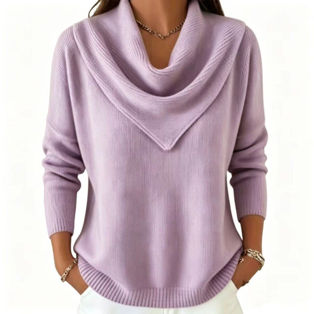 A woman wearing a light lavender knit sweater with a wide draped cowl neckline, long sleeves, and a relaxed fit, paired with white pants against a plain white background.