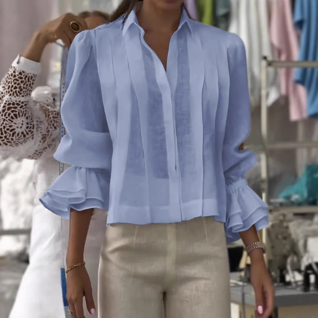 Person wearing a light blue blouse with ruffled sleeves in a clothing store.