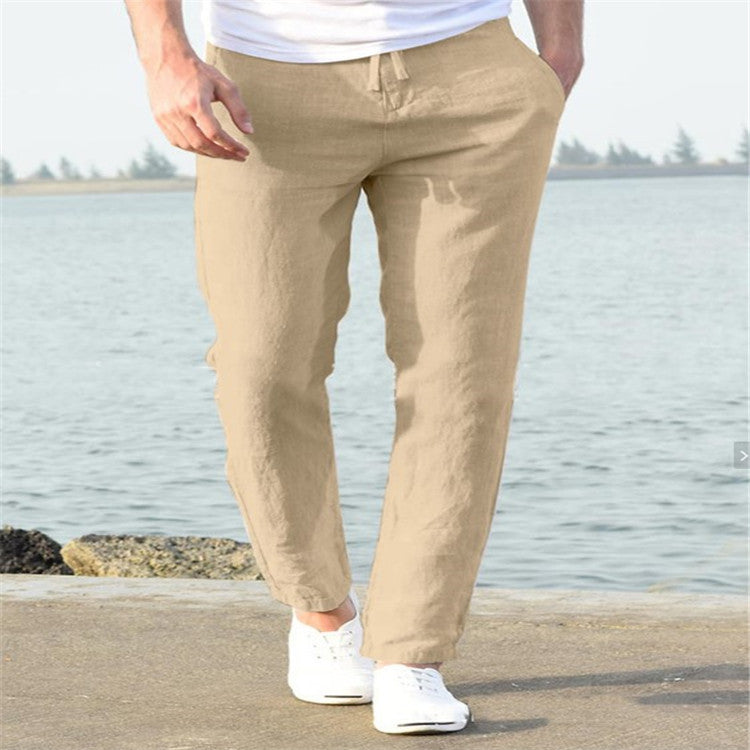 Person wearing beige pants and white shoes standing by a body of water.