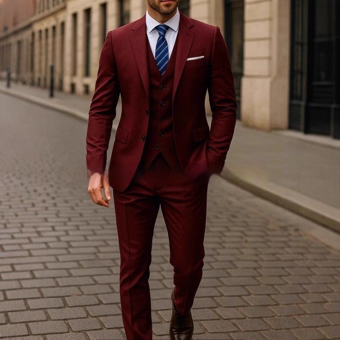 Man wearing a burgundy suit with a blue tie on a city street.