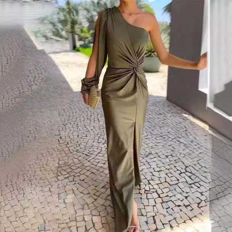Woman in a green one-shoulder dress standing on a stone pavement.