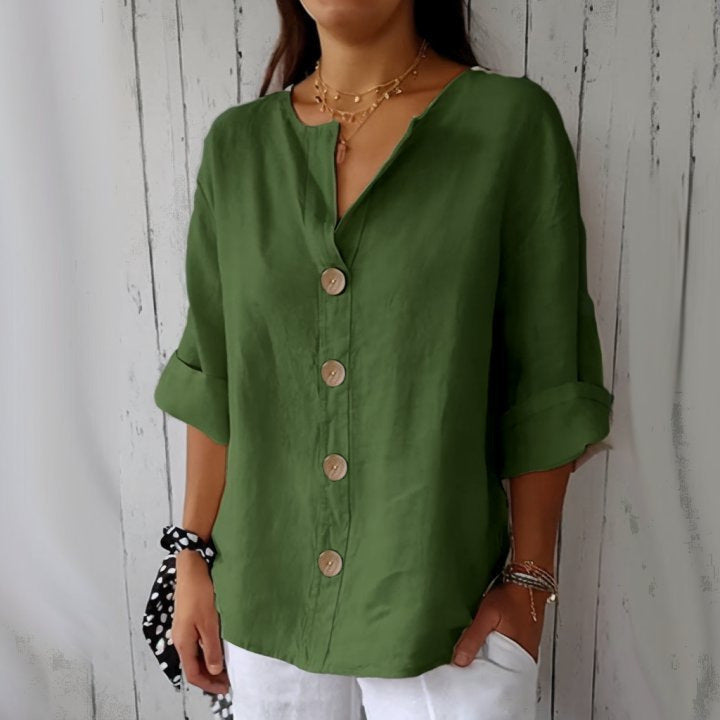 Person wearing a green shirt with rolled-up sleeves against a wooden background