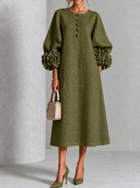 An olive green linen midi dress with voluminous balloon sleeves and textured rosette cuffs, shown on a model holding a small beige handbag.
