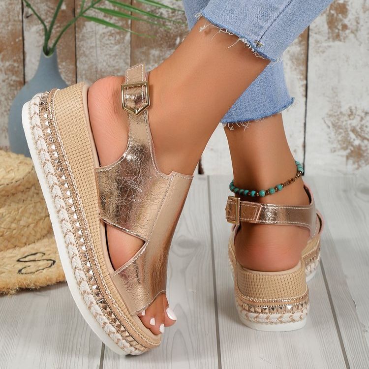 Gold espadrille sandals worn with denim jeans on a wooden floor.