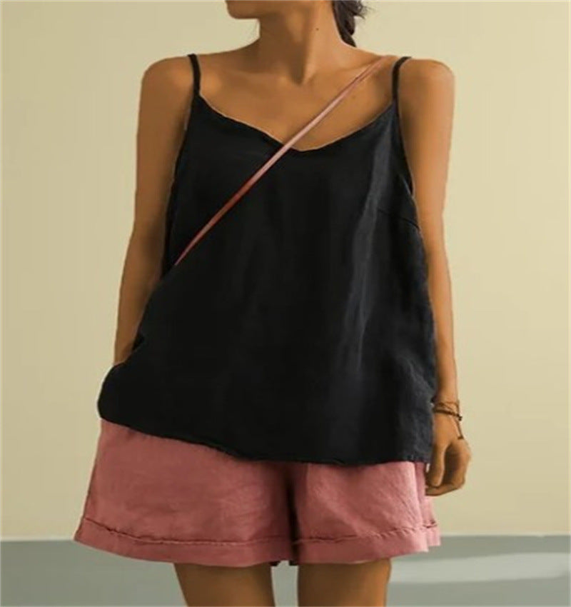 Person wearing a black top and pink shorts with a beige background