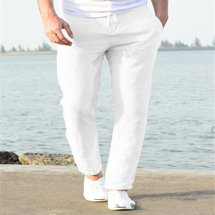 Person wearing white pants standing by a body of water.