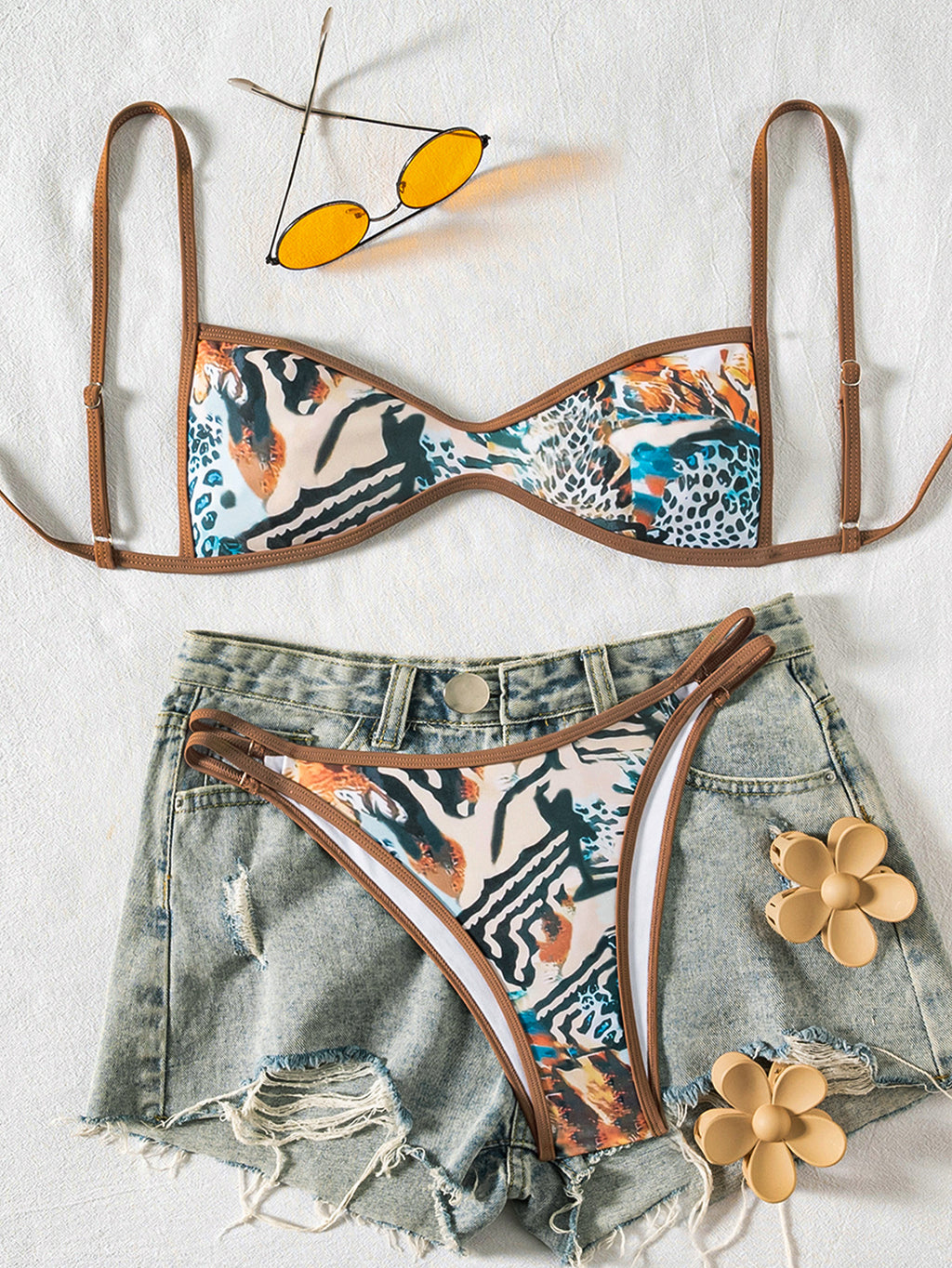 Floral bikini set with denim shorts and sunglasses on a light background