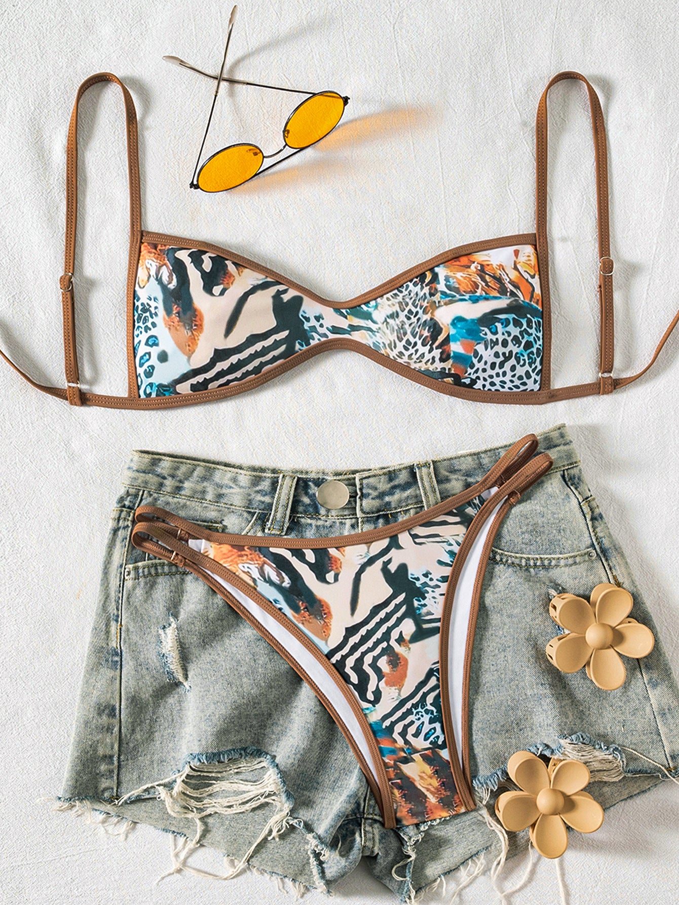 Floral bikini set with denim shorts and sunglasses on a light background