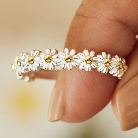 Close-up of a hand wearing a daisy flower ring with gold centers.