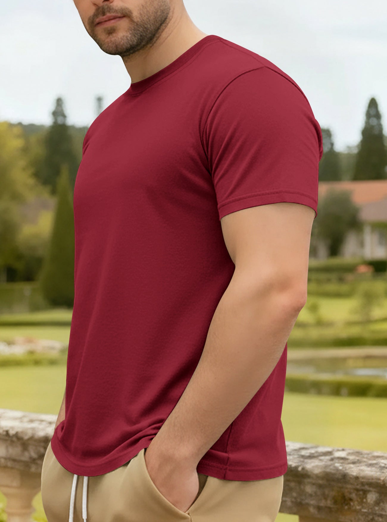 Man wearing a red t-shirt outdoors with greenery in the background