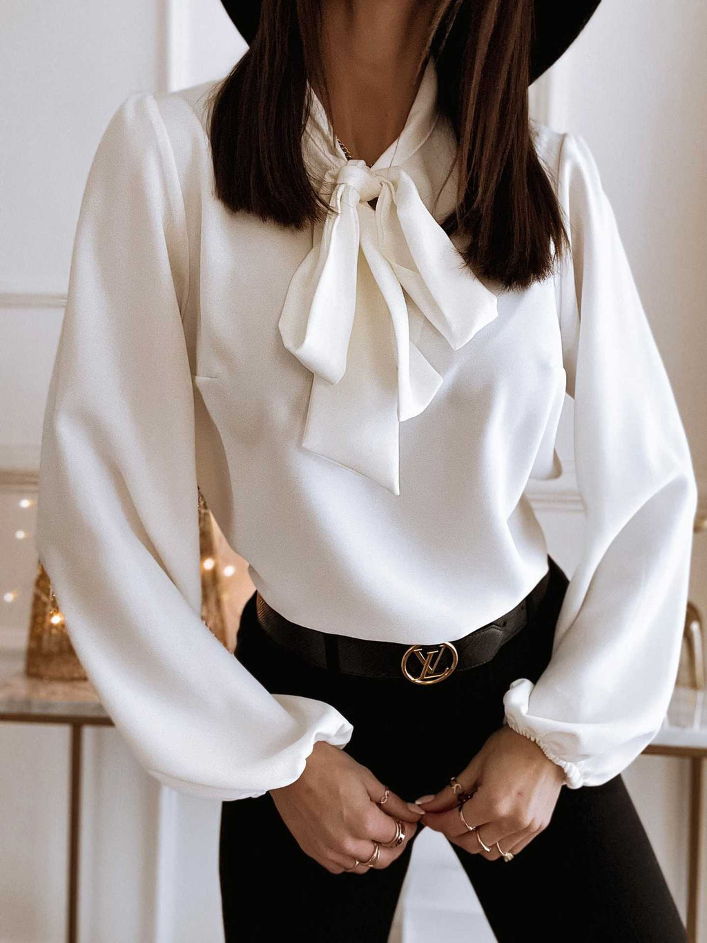 White blouse with a bow tie worn by a person indoors.