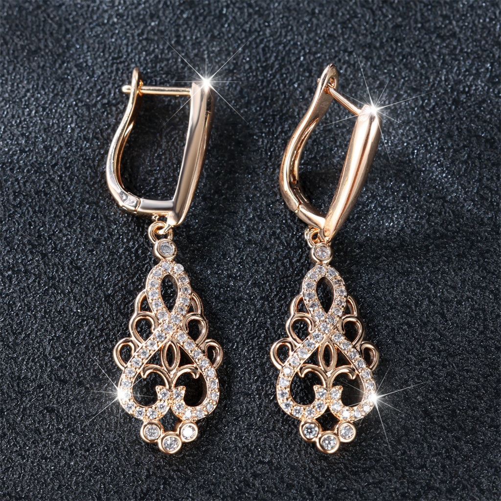 Pair of gold earrings with intricate designs on a dark background