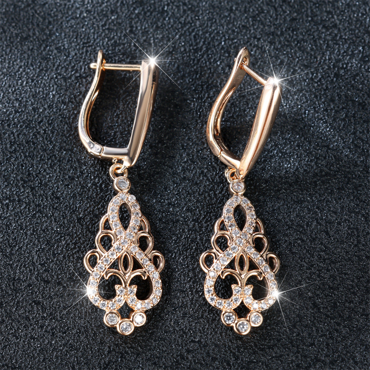 Pair of gold earrings with intricate designs on a dark background