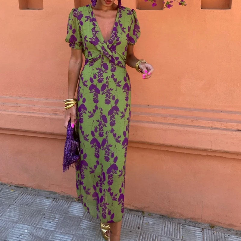 Woman wearing a green and purple floral dress against an orange wall.