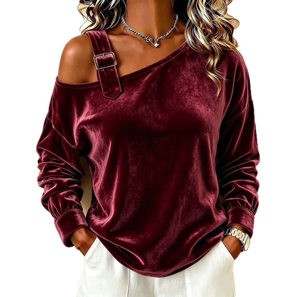 A woman wearing a burgundy velvet off-the-shoulder long-sleeve top with a decorative strap detail and buckle, paired with white pants, shown against a plain white background.