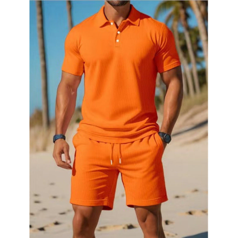 Person wearing an orange polo shirt and shorts set on a beach with palm trees in the background.