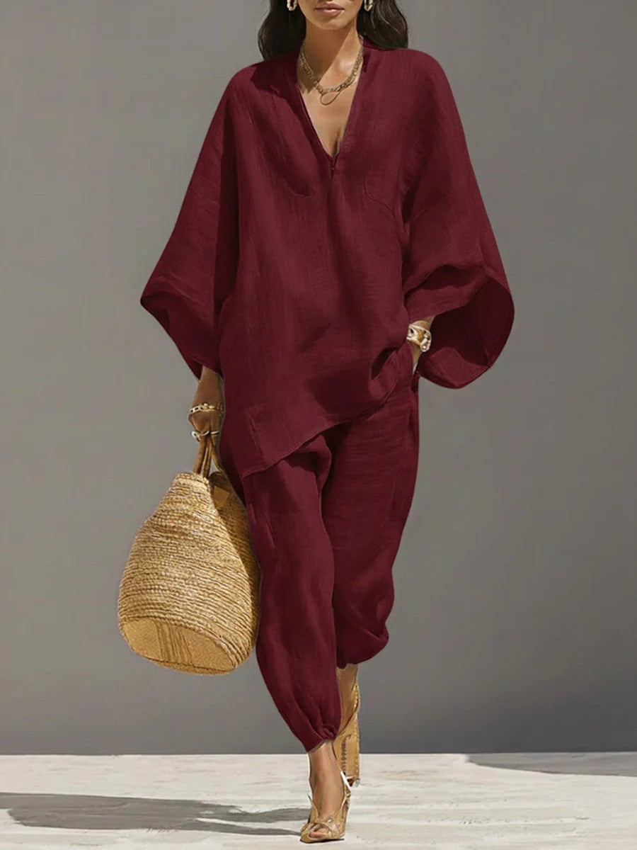 Woman wearing a burgundy outfit with a straw bag against a gray background