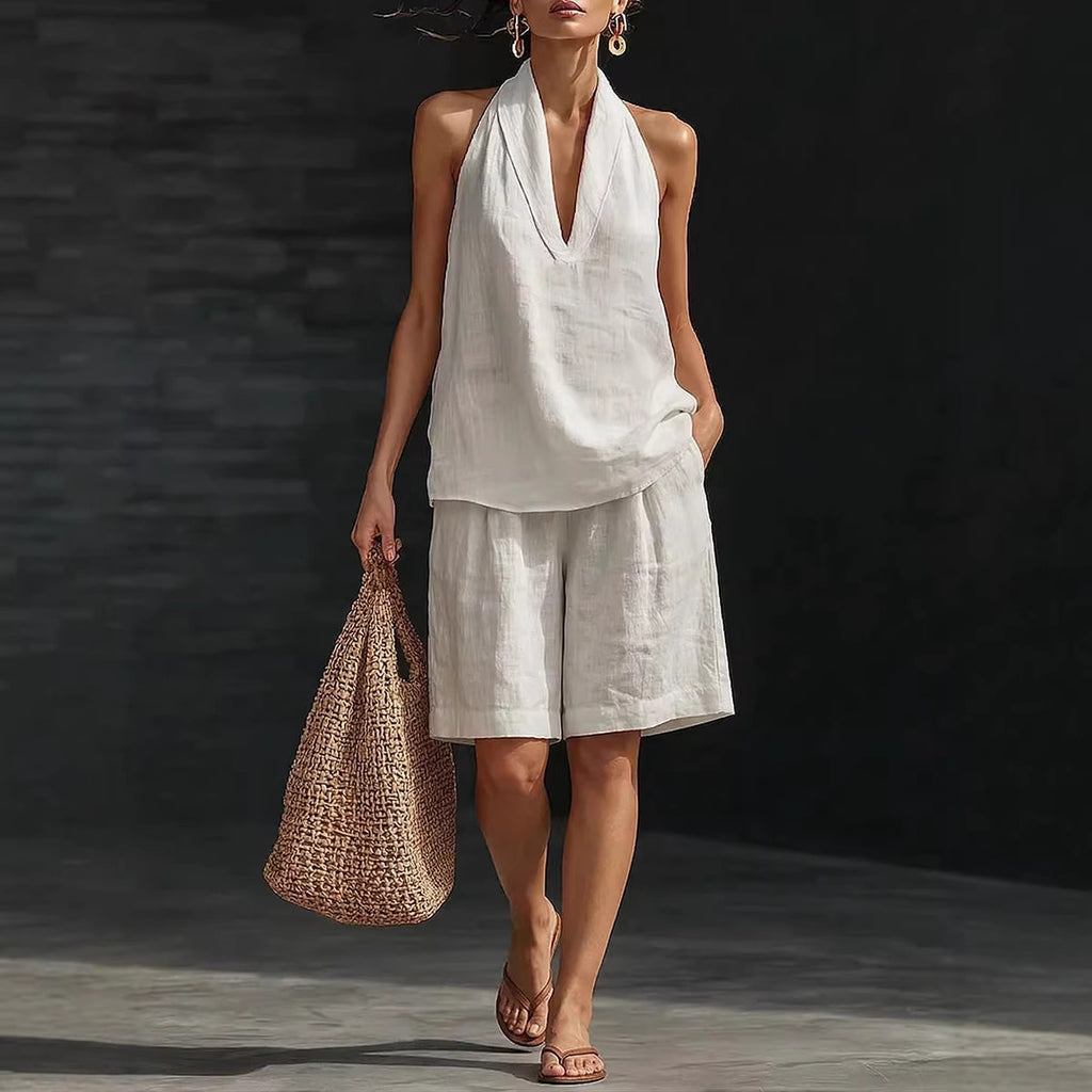 Woman in a white outfit holding a woven bag against a dark background